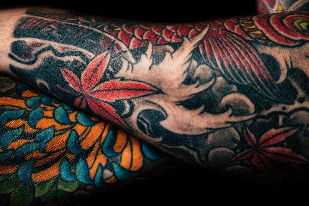 Tatuagem com pigmentos preto, vermelho, laranja e azul